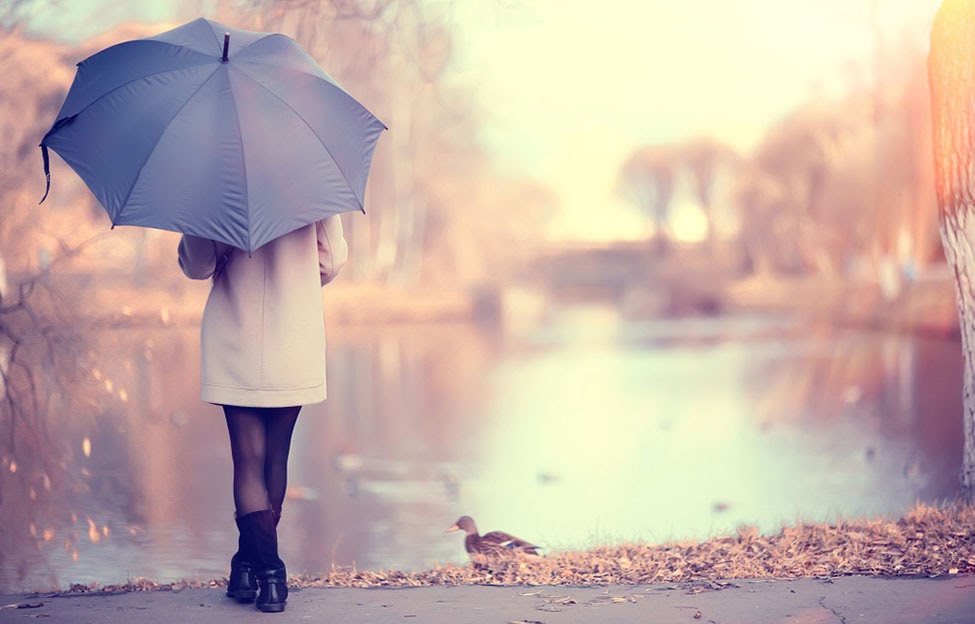 woman standing by water with umbrella